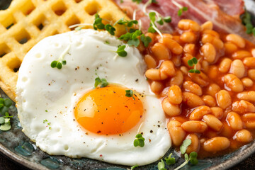 Wall Mural - Potato waffles with fried egg, bacon and baked beans. Morning breakfast