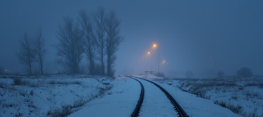 Illuminated snow-covered railway at night. Atmospheric winter landscape. Mysterious blue light. Transportation. safety, danger concepts