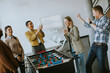 © BGStock72 - Young casual multiethnic business people playing table football and relaxing at office