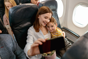 Wall Mural - Happy mother and daughter making selfie in airplane