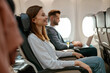© Friends Stock - Cheerful woman sitting in passenger chair in airplane