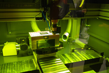 Poster - Industrial laser equipment close-up. Camera with a laser machine. Laser machine chamber behind transparent glass. Industrial equipment is illuminated in neon green. Engraving equipment