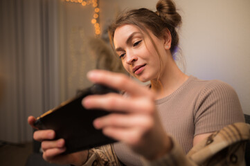 Wall Mural - Girl gamer plays a video game on a portable game console at home in the room. Close-up. Video games, mobile games, virtual reality, cyberspace, esports, entertainment.