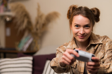 Wall Mural - A cute girl with a joystick plays a video game at home in the room. Interesting entertainment, gaming, communication, online games with friends, win, win, game strategy.