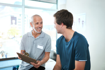 Wall Mural - Keeping a full record of his patients health. Cropped shot of a handsome mature male physiotherapist having a consultation with a patient.