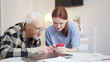 © iaginzburg - Grandpa is learning to use the phone. Social worker teaches pensioner