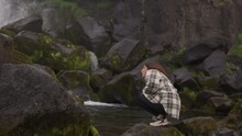 Woman Crouching On Rock By Oxararfoss Waterfall