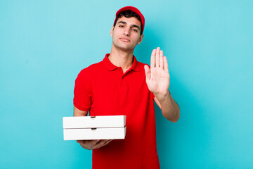 Poster - handsome hispanic man looking serious showing open palm making stop gesture. delivery pizza concept