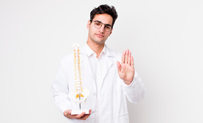 Poster - handsome hispanic man looking serious showing open palm making stop gesture. spine specialist concept