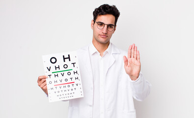 Poster - handsome hispanic man looking serious showing open palm making stop gesture. optical vision test concept