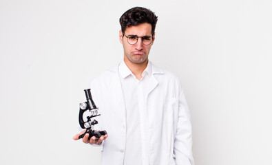 Wall Mural - handsome hispanic man feeling sad and whiney with an unhappy look and crying.. scientist with microscope concept