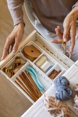 Sticker - Female hands putting scissors into drawer with sewing accessories neatly placing organizing top view