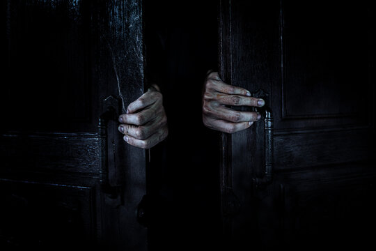 Ghost hands open the wooden door from the inside of the old dark room. Filled with spider webs