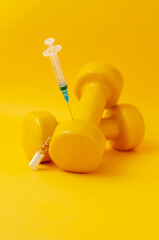 Poster - syringe stuck in a dumbbell, a medical ampoule lies next to it, a yellow background, a vertical snapshot. the concept of doping in sports, steroids, testosterone and other drugs banned in sports.