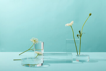 A front view of transparent podium decorated with flower and blue background with blank space for advertising 