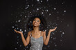 © Westend61 - Smiling young woman with eyes closed standing under falling confetti against black background