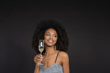 Smiling Young Woman Holding Champagne Flute Against Black Background