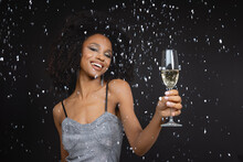 Happy Young Woman Holding Champagne Flute Against Black Background