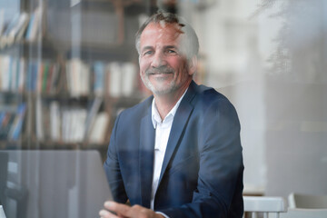 Smiling businessman with laptop sitting at cafe
