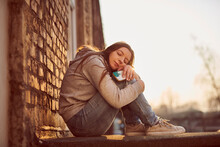 Young Woman Hugging Knees Enjoying The Evening Sun
