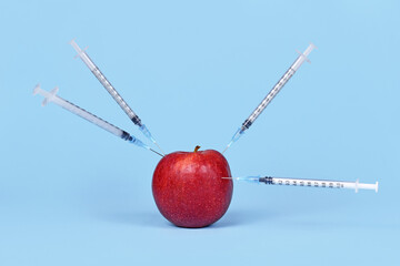 Wall Mural - apple fruit being injected with syringes. concept for genetically modified organism