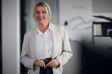 Smiling Businesswoman With Blond Hair Standing In Office