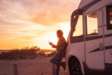 Man Leaning On Camper Van And Using Smart Phone