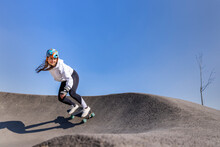 Smiling Young Woman Practicing Skateboarding At Pump Track On Sunny Day