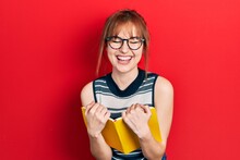 Redhead Young Woman Reading A Book Wearing Glasses Smiling And Laughing Hard Out Loud Because Funny Crazy Joke.
