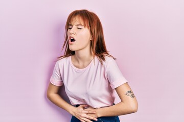 Canvas Print - Redhead young woman wearing casual pink t shirt with hand on stomach because nausea, painful disease feeling unwell. ache concept.