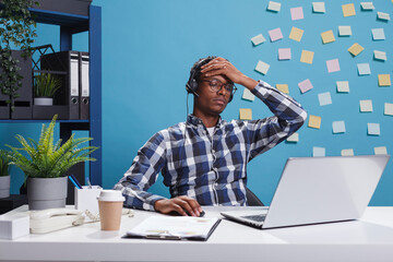 Wall Mural - tired and stressed customer support operator with headache in teleconversation with potential client