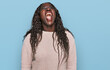 © Krakenimages.com - Young african woman wearing wool winter sweater angry and mad screaming frustrated and furious, shouting with anger. rage and aggressive concept.