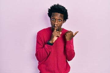 Sticker - Young african american man wearing casual clothes asking to be quiet with finger on lips pointing with hand to the side. silence and secret concept.