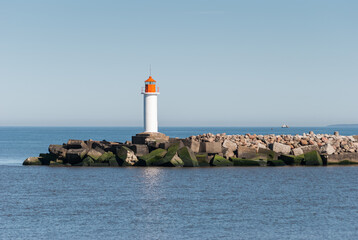 Wall Mural - Mole with lighthouse and concrete blocks in sunny day, Ventspils, Latvia.