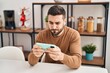 © Krakenimages.com - Young hispanic man using smartphone sitting on table at home