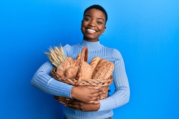 Sticker - Young african american woman holding wicker basket with bread smiling with a happy and cool smile on face. showing teeth.