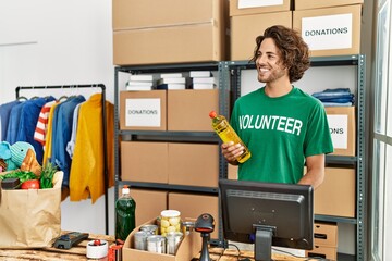 Wall Mural - Young hispanic volunteer man smiling happy working at charity center.