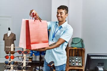 Wall Mural - Young hispanic man working as shop assistant at retail shop