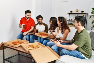 Wall Mural - Group of young friends smiling happy eating italian pizza sitting on the sofa at home.