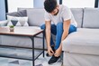 © Krakenimages.com - Young arab man tying shoe sitting on sofa at home