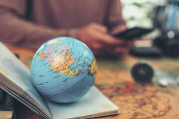 Globe, whole world  on passport and focus United states country and man use phone . The route map on the table. Travel , Adventure and Discovery concept.