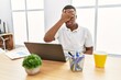 Young african man working at the office using computer laptop covering eyes with hand, looking serious and sad. sightless, hiding and rejection concept