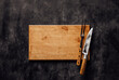 Butcher. Vintage meat knife and fork on cutting board over stone background