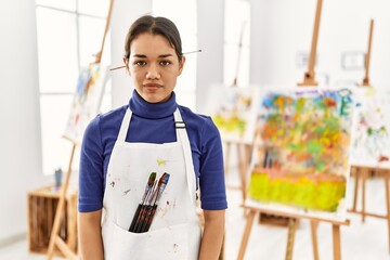 Wall Mural - Young brunette woman at art studio relaxed with serious expression on face. simple and natural looking at the camera.