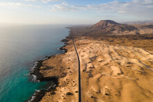 Aerial View Of A Road Along The Coast Crossing The Sand Dune Natural Park In Corralejo, Fuerteventura, Canary Islands, Spain.