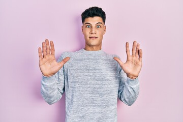 Sticker - Young hispanic man wearing casual clothes afraid and terrified with fear expression stop gesture with hands, shouting in shock. panic concept.