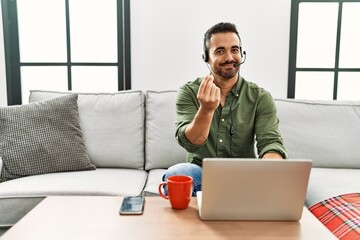 Poster - Young hispanic man with beard wearing call center agent headset working from home doing money gesture with hands, asking for salary payment, millionaire business