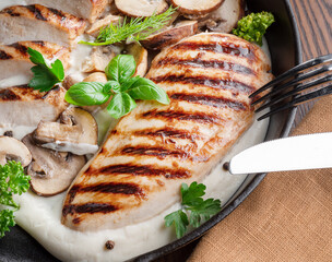 Wall Mural - Roasted chicken fillet and mushrooms with herb in the frying pan on the wooden table close-up.