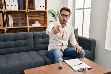 Sticker - Young hispanic man with beard working at consultation office pointing displeased and frustrated to the camera, angry and furious with you