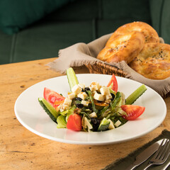 Sticker - Photo of Greek salad and a basket of bread on a wooden table